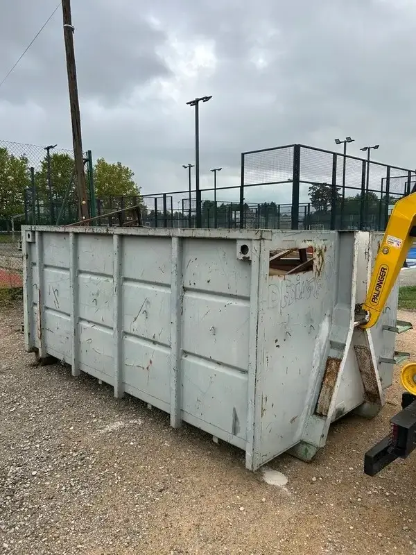 Benne JDM grise posée sur un terrain de chantier