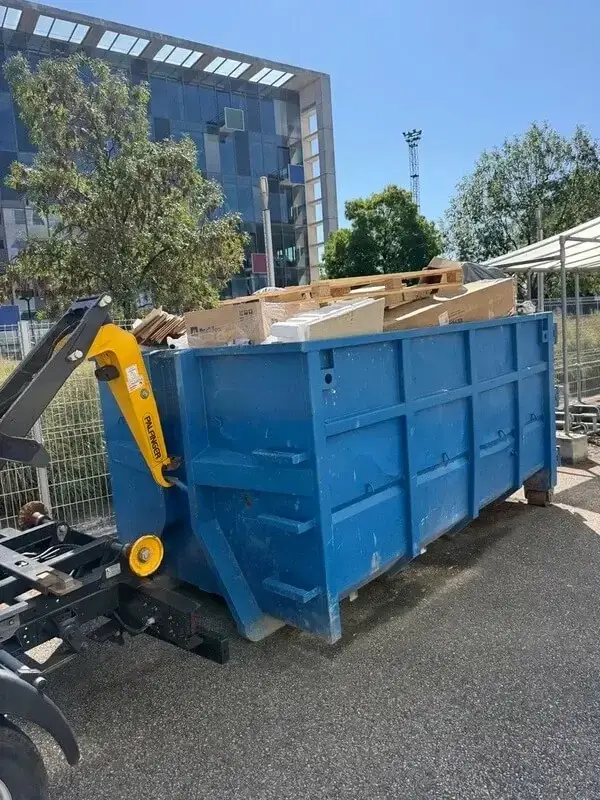 Benne JDM chargée de cartons et de palettes, accrochée au bras du camion